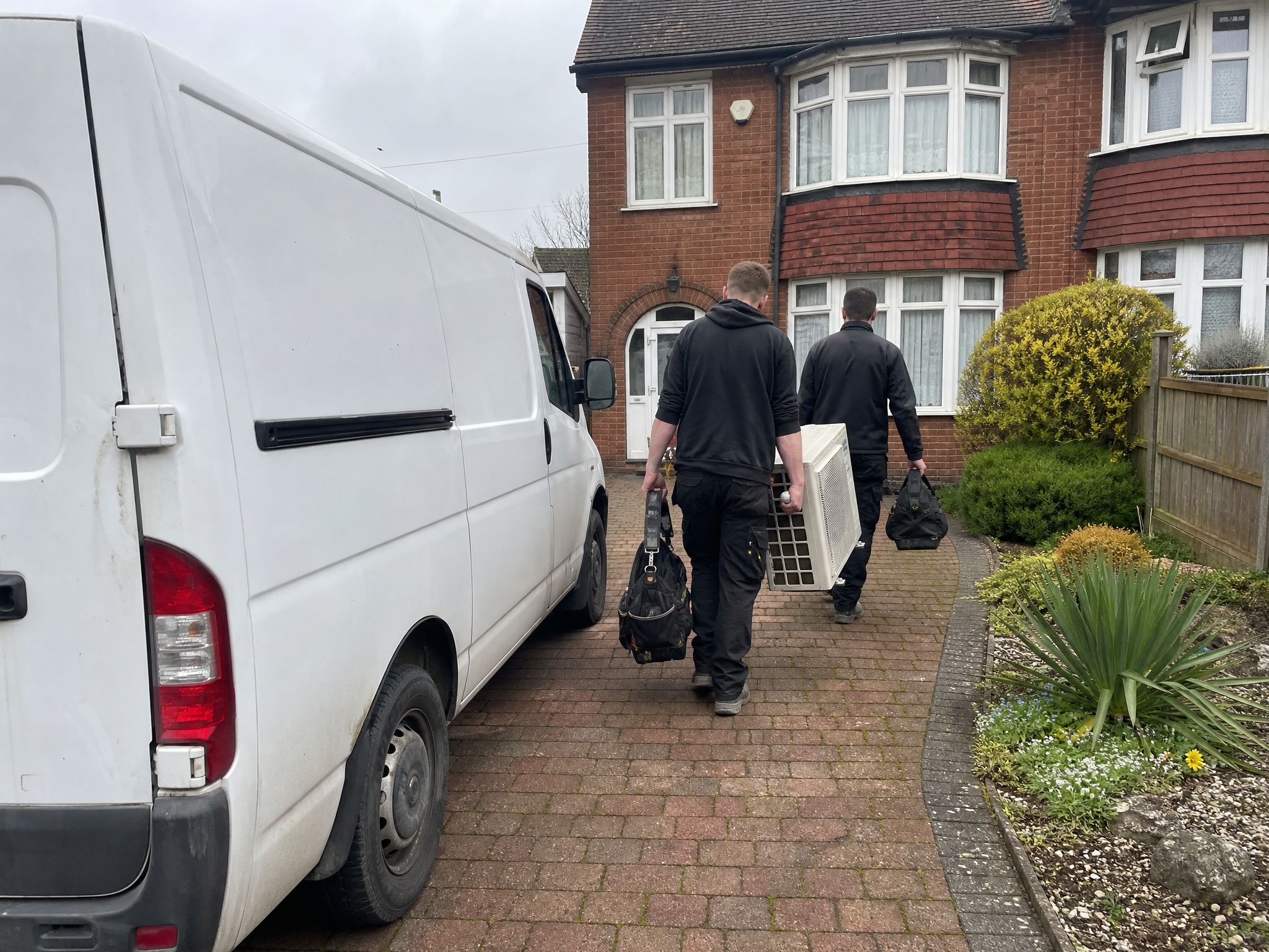 Heat pump installers with a plain white van outside a house in Walsall