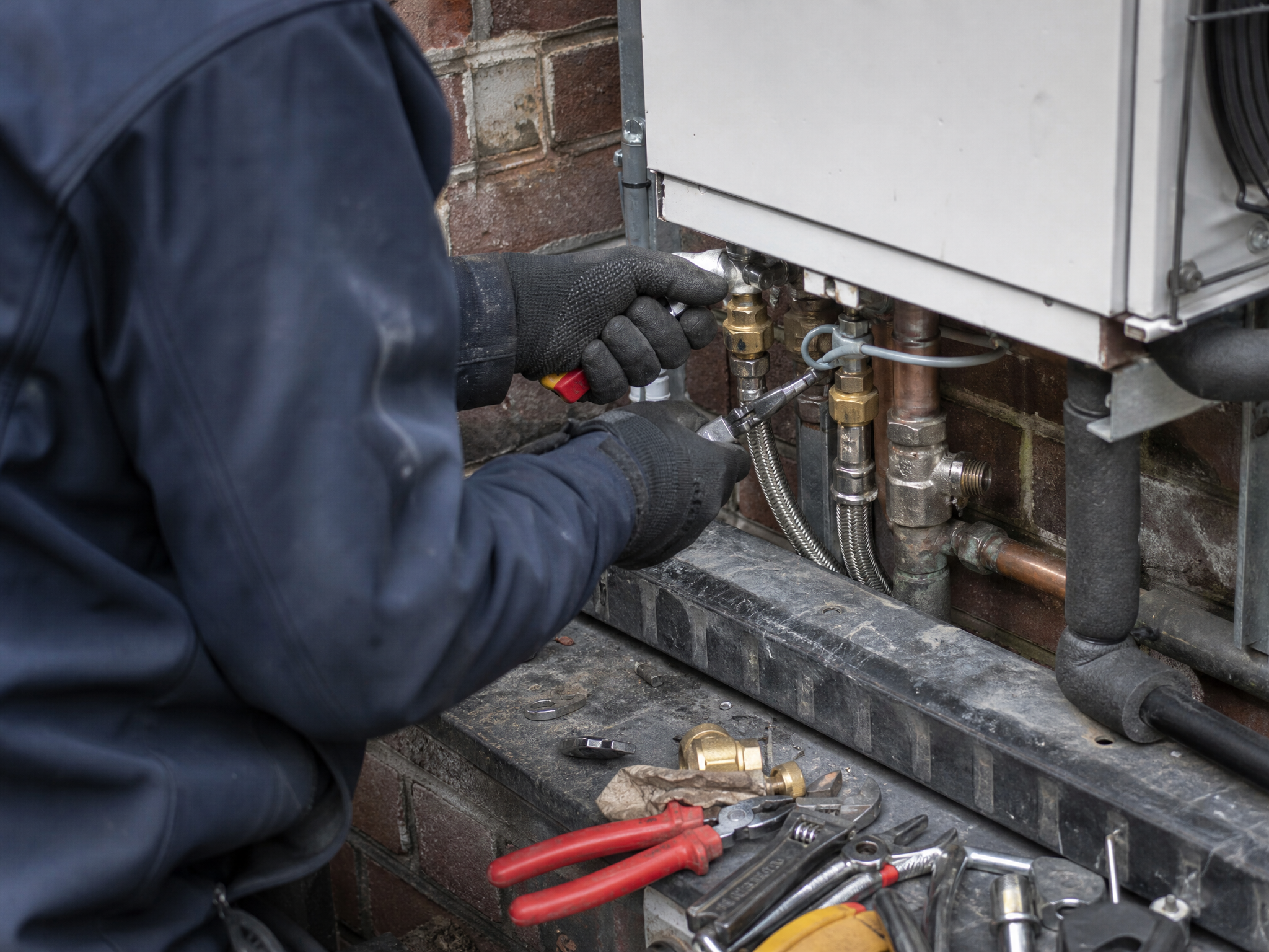 Professional installer carrying out gas boiler to heat pump replacement in a UK residential property