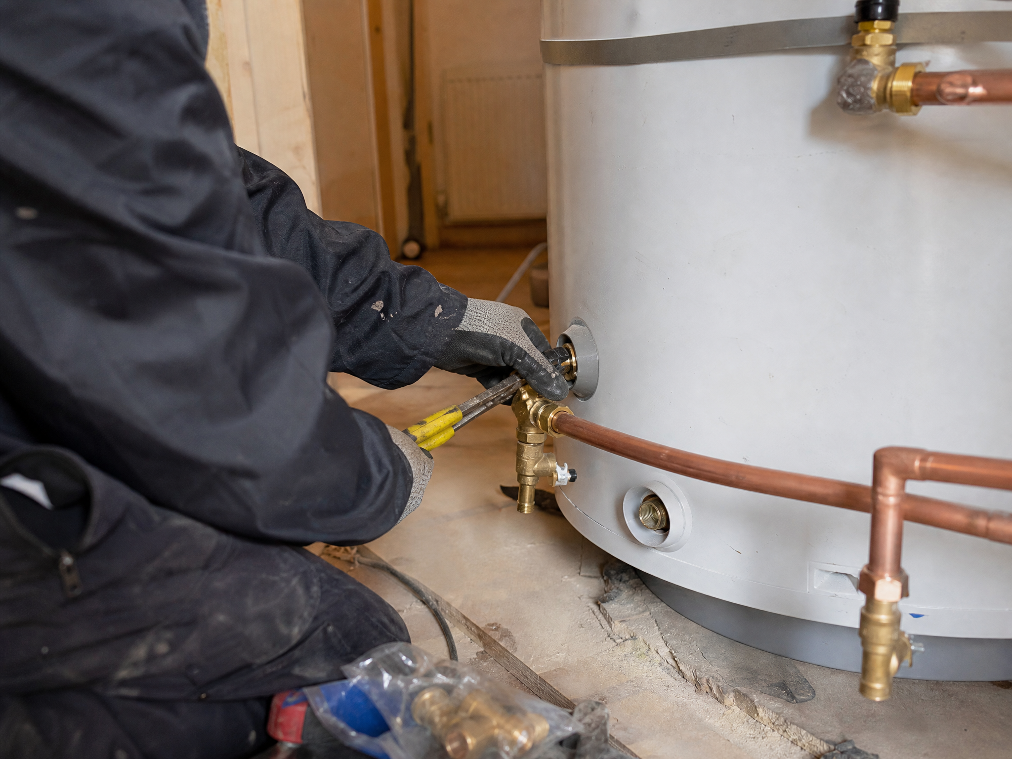 Professional installer carrying out hot water cylinder installation in a UK residential property
